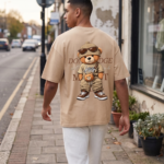 Man wearing a Navalook beige oversized t-shirt with a teddy bear graphic walking on a city street