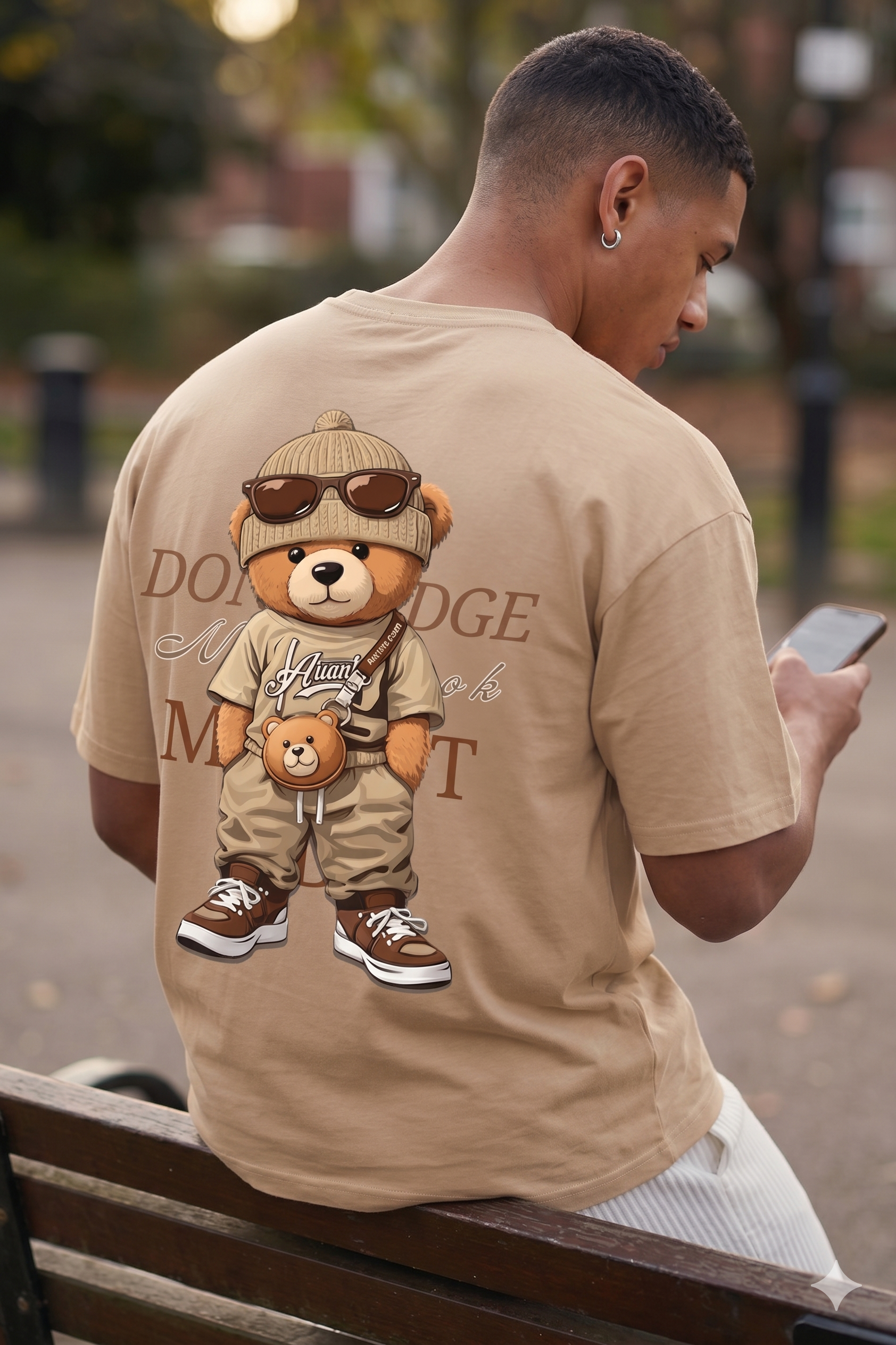 Man wearing a Navalook beige oversized t-shirt with a teddy bear graphic walking on a city street