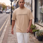 Man wearing a Navalook beige oversized t-shirt with a teddy bear graphic walking on a city street