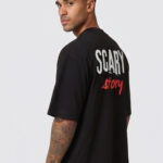 Man wearing a black oversized streetwear T-shirt with 'Scary Story' printed on the back in white and red text.